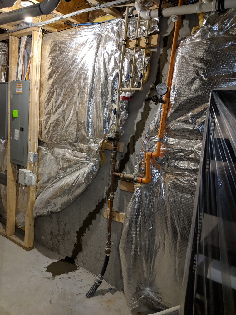 OBW inspector measuring and photographing vertical basement wall crack