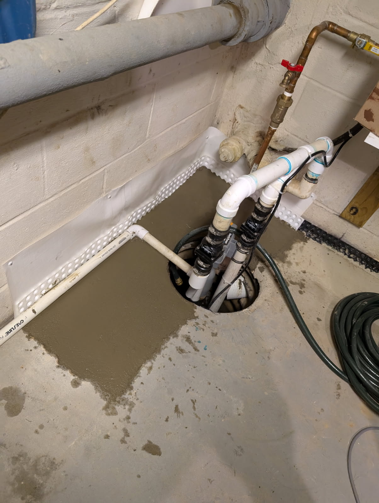 Backup sump pump with drainage matting and freshly poured concrete
