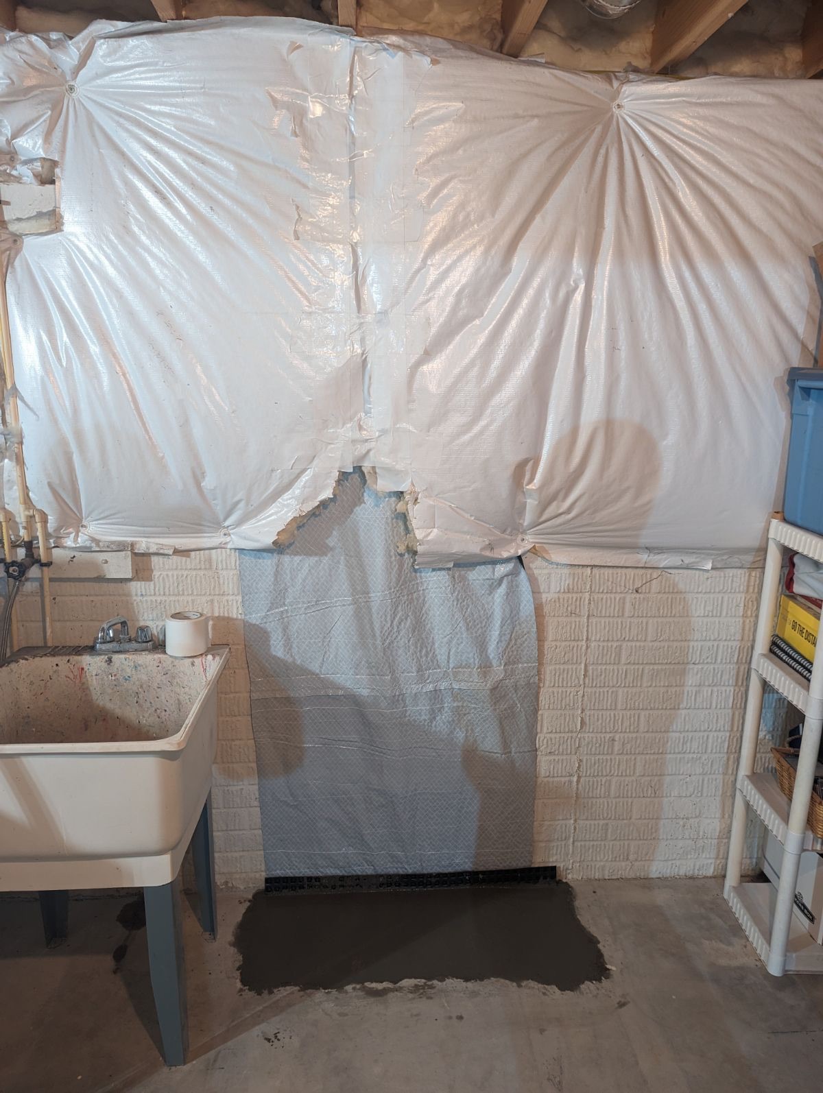 New vapor barrier installation on basement wall with drainage matting visible