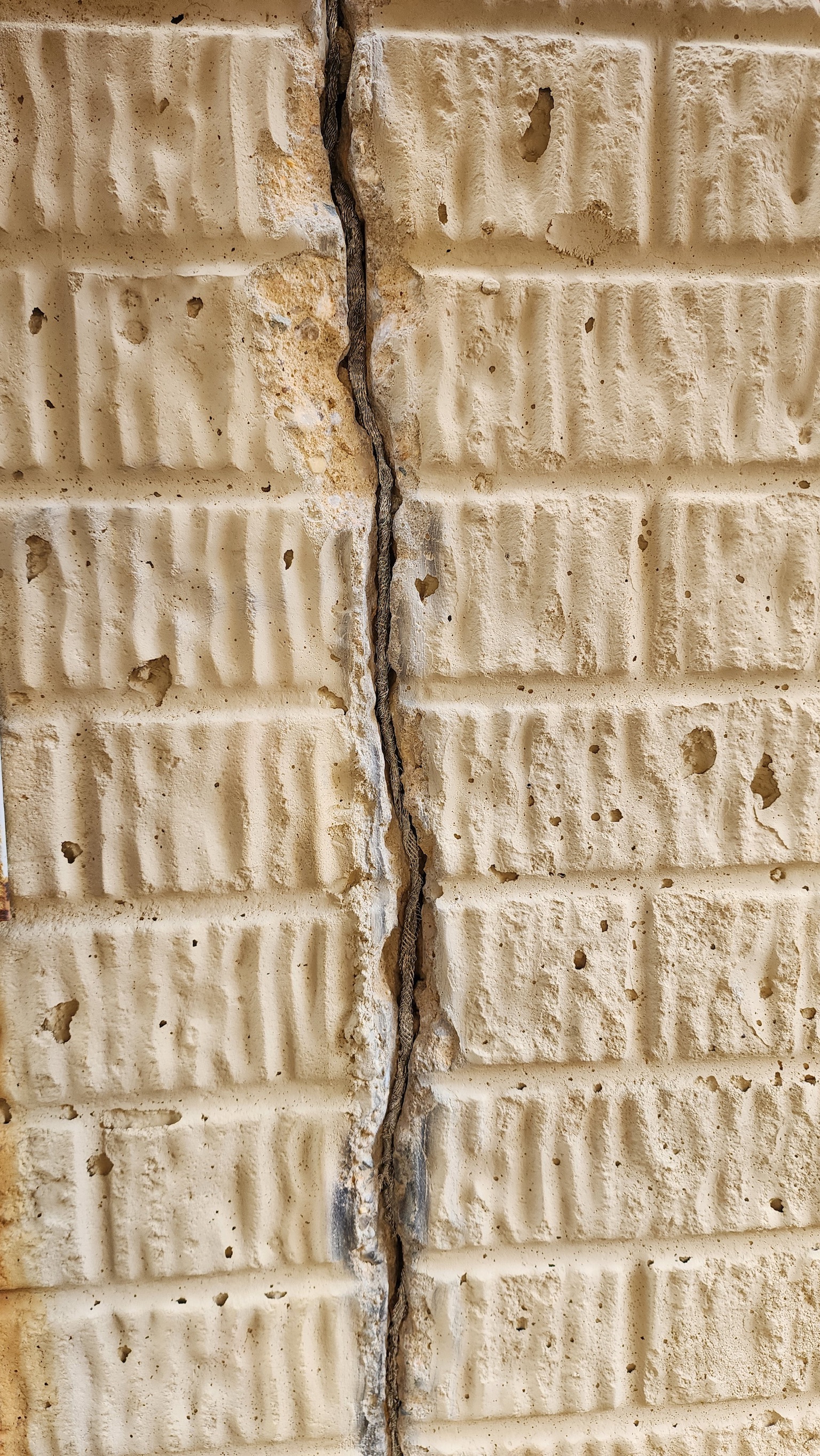 Deep vertical crack in concrete block foundation — classic settlement damage sign