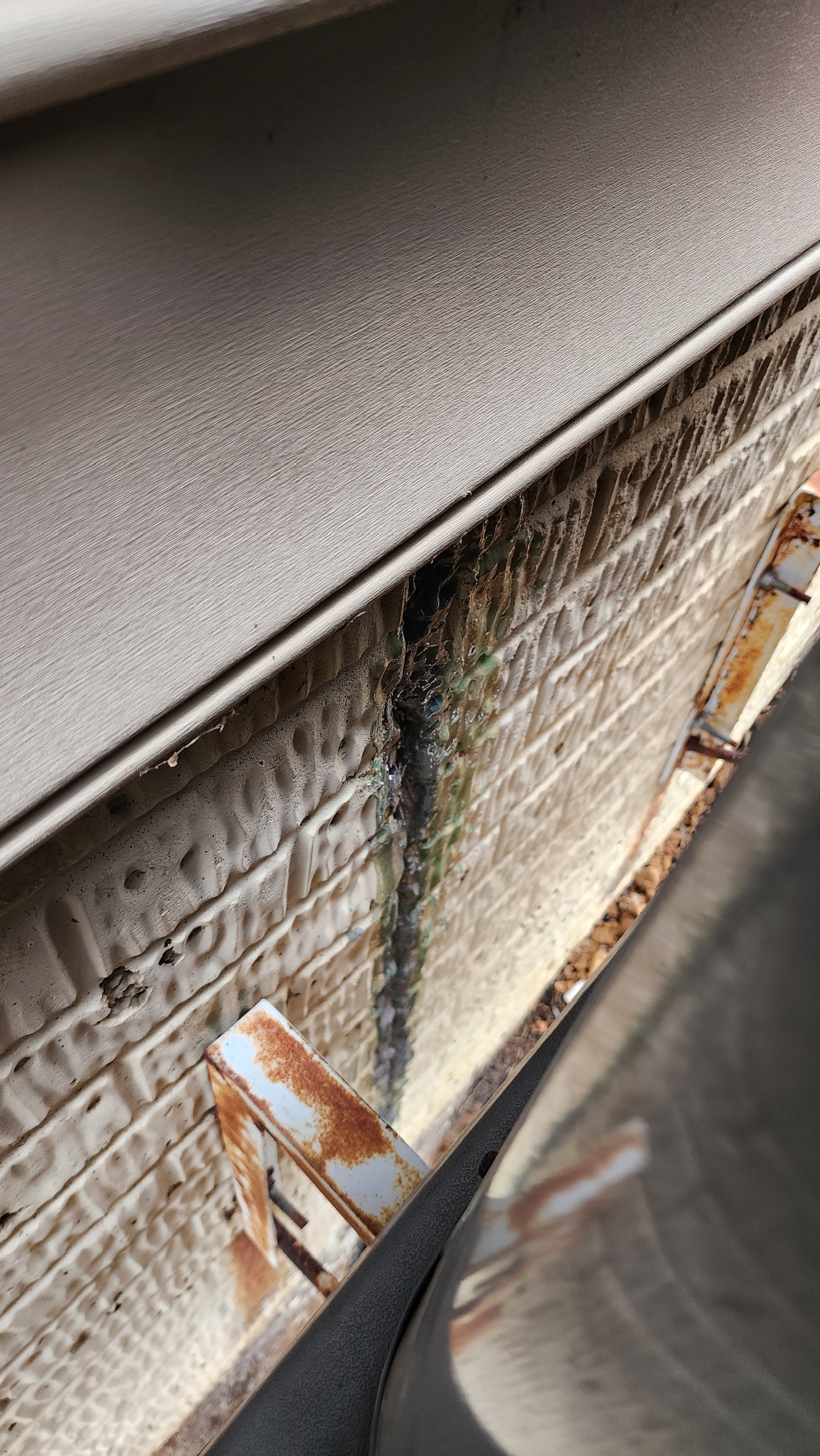 OBW inspector examining vertical crack with epoxy injection in block foundation